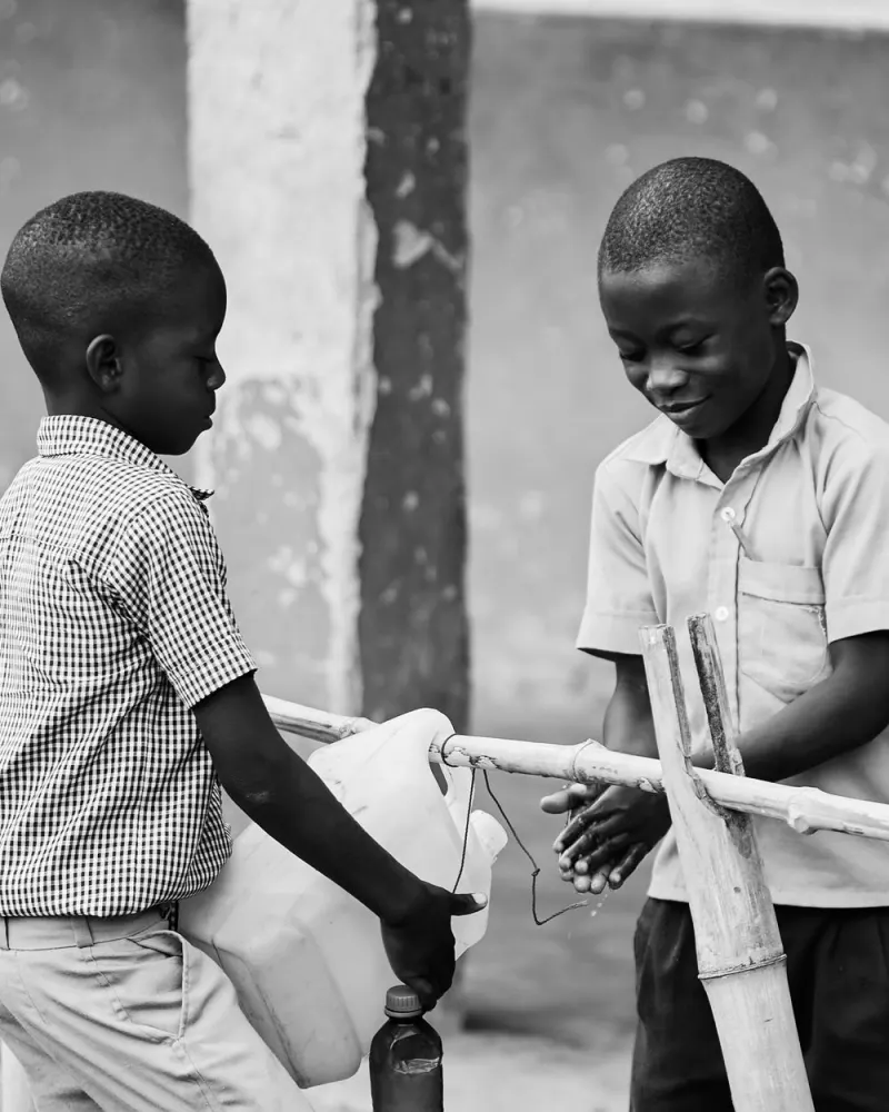 Children washing hands from a bottle on a rack